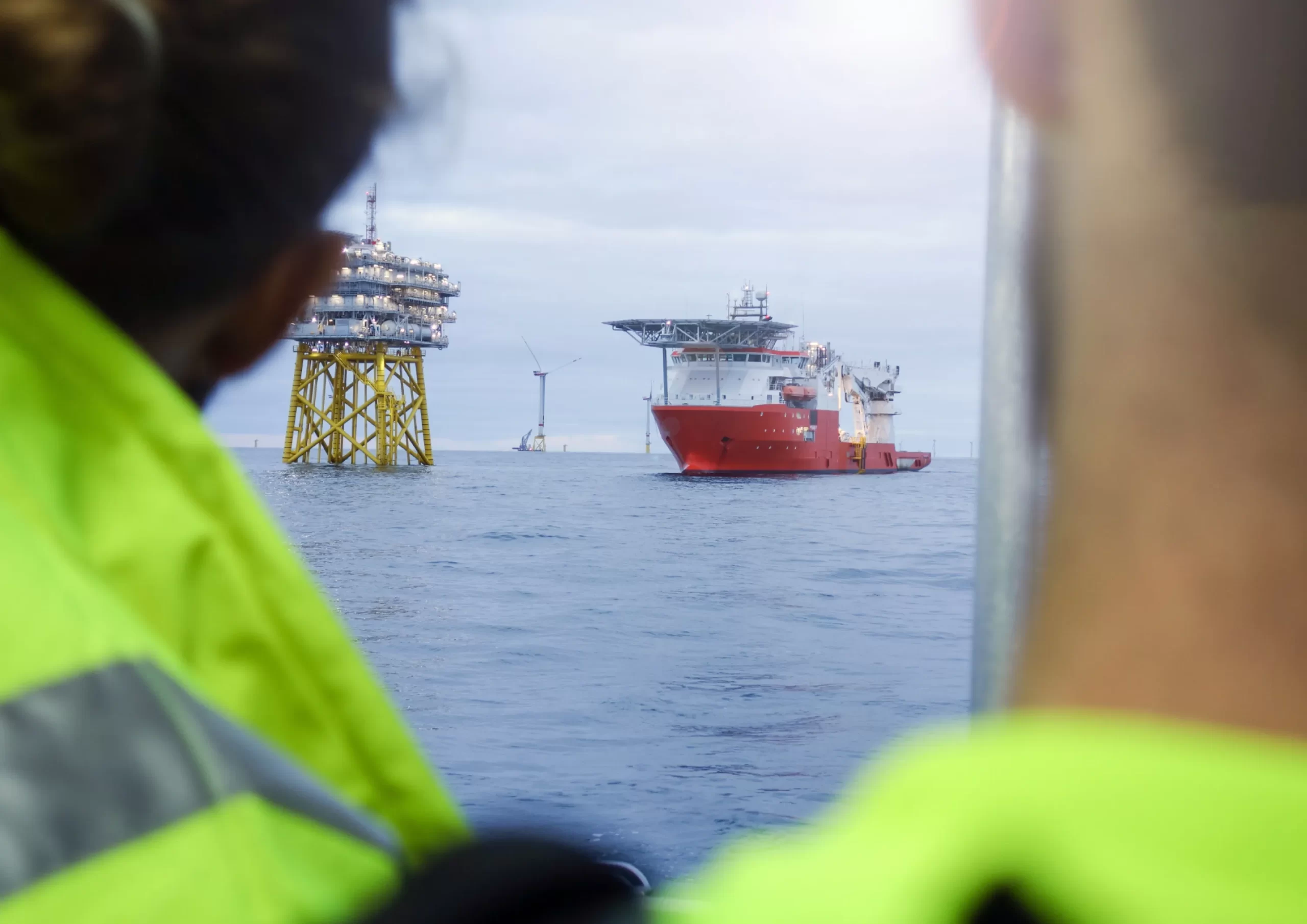 Seen from the perspective of marine workers, a support vessel and an offshore platform are working in the sea.