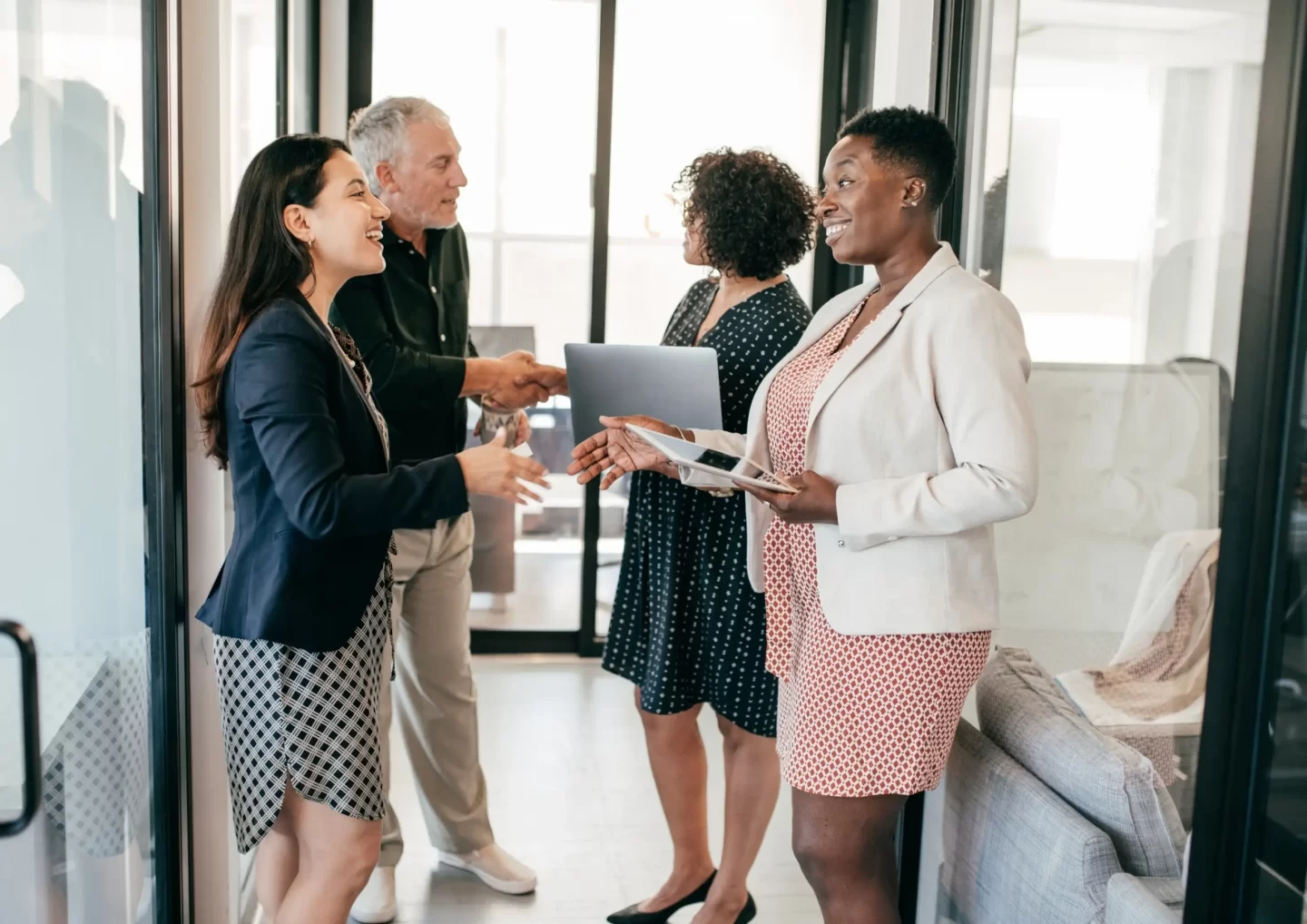 a group of recruitment professionals is engaging in a friendly conversation and handshake in the office