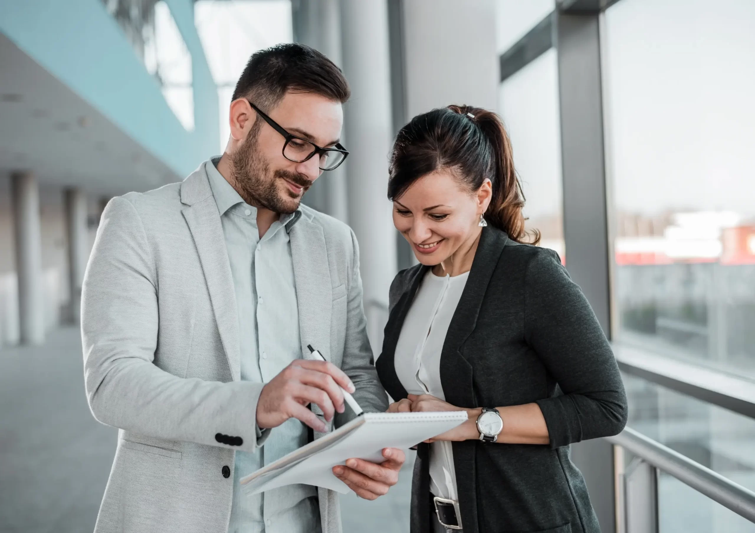 Two professionals review notes together in the office