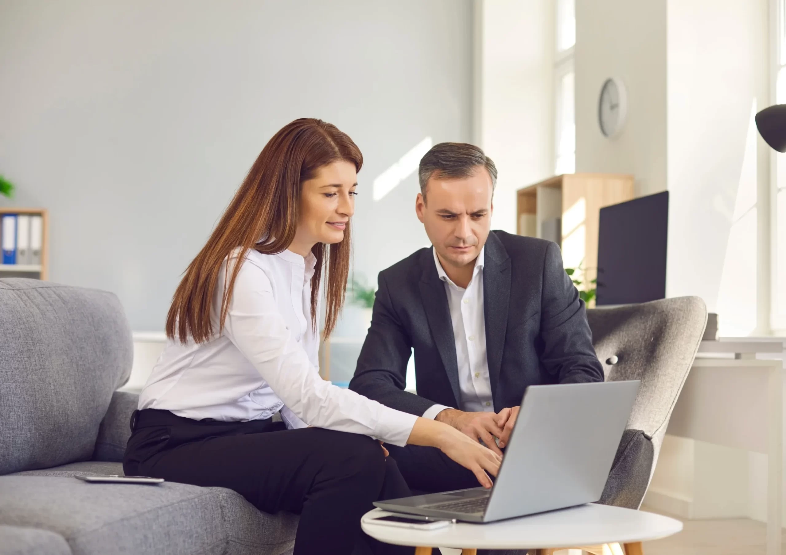 Two colleagues collaborate on a project using a laptop in a relaxed office