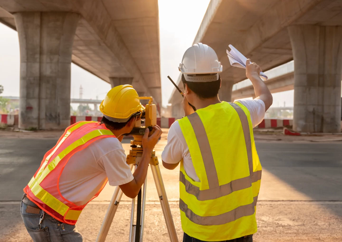 Engineers conducting a site survey under a bridge at sunset, representing operations and maintenance services in Gabon.